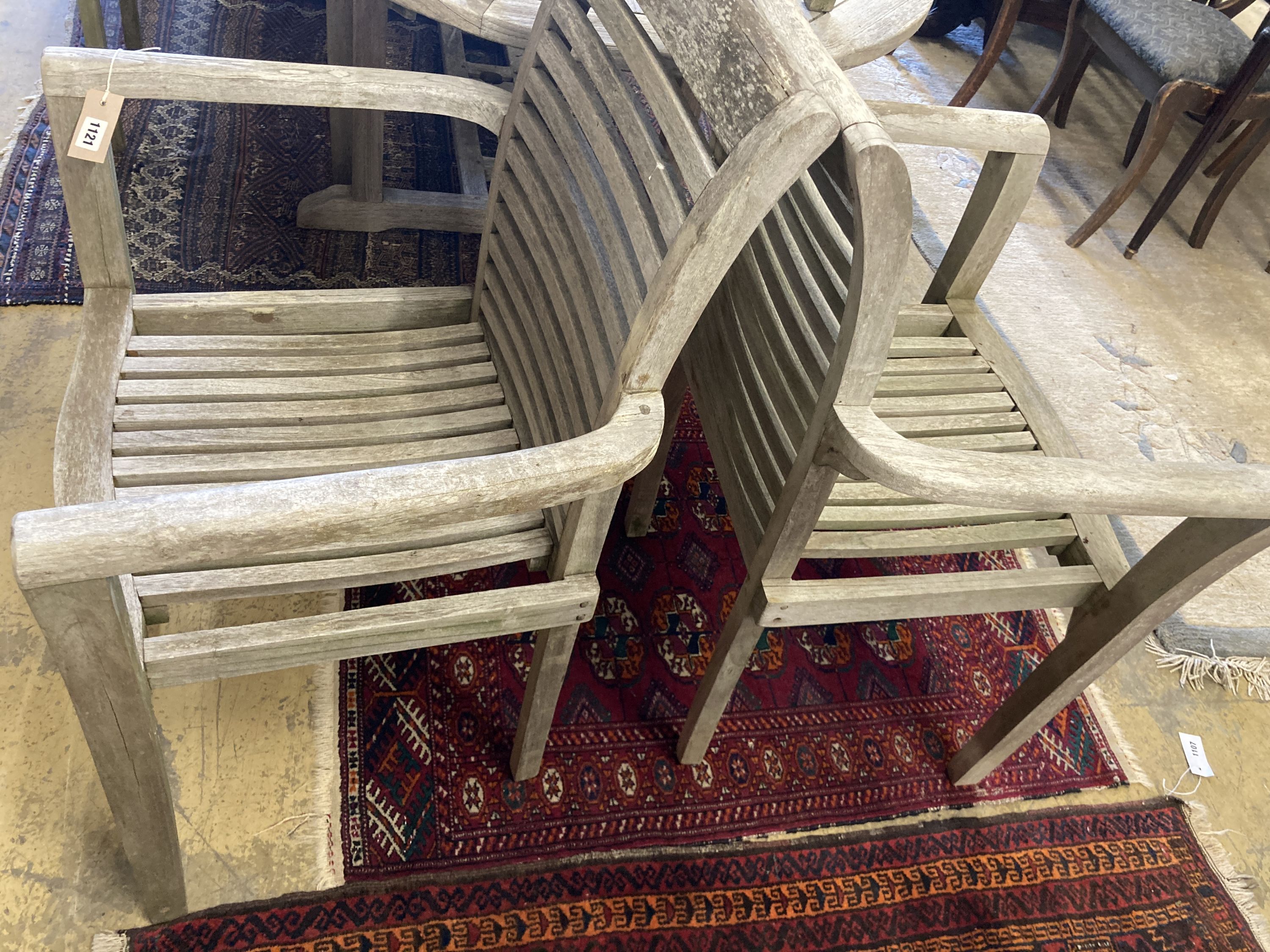 A weathered teak extending garden table, length 240cm extended, depth 100cm, height 77cm together with a set of seven weathered teak elbow chairs
